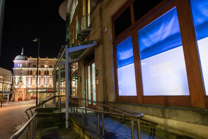 The Bank, a building adjacent to Sheffield Theatres, is lit up in blue at night.