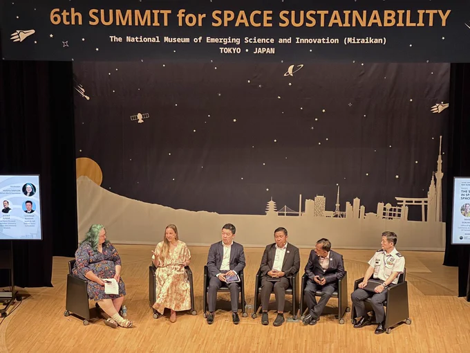 Mariel Borowitz (2nd from left) speaks on stage with five other panelists under a banner reading, "6th Summit for Space Sustainability"