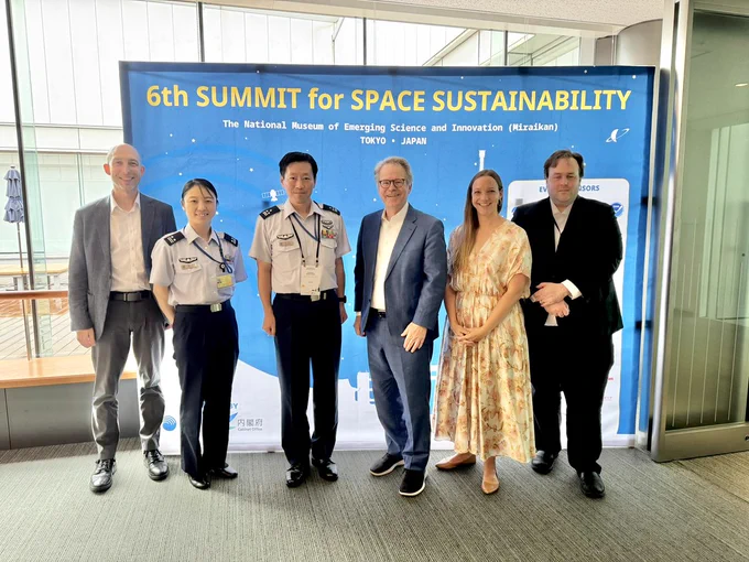 OSC and JASDF representatives pose in front of a backdrop reading "6th Summit for Space Sustainability"