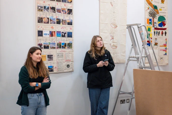 two girls examine a wall during an exhibition installation