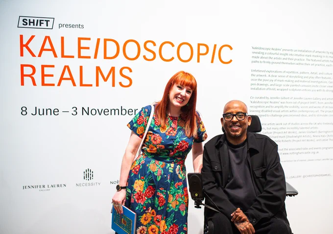 A photo of exhibition curators Jennifer Gilbert from Jennifer Lauren Gallery and artist Christopher Samuel in front of the exhibition introduction and text