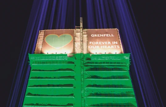Photo of Grenfell Tower at night with green lights shining on it