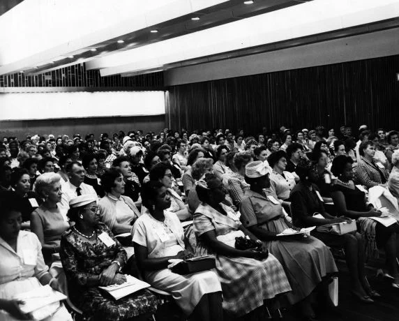 500 partners of UAW members attend a meeting at Solidarity House—UAW's headquarters in Detroit, Michigan—to discuss the union’s collective bargaining and legislative programs. (undated black and white photo)