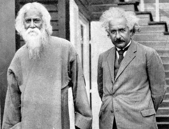 Albert Einstein and Rabindranath Tagore standing together on steps outside a building, both looking towards the camera, capturing a historical meeting of two intellectual figures.