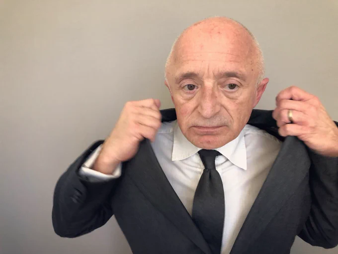Rick adjusting his suit jacket as he takes a picture of himself.