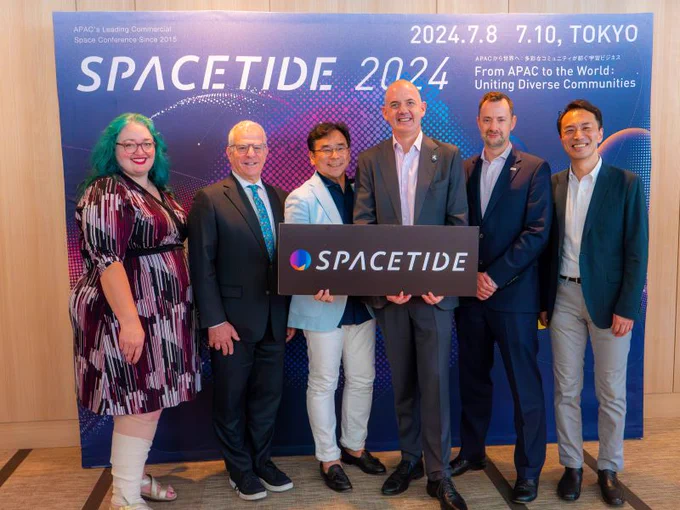 UK Space Agency CEO, Dr Paul Bate with Astroscale Group Chief Operating Officer, Chris Blackerby, Co-Founder, President and CEO of SPACETIDE, Masayasu Ishida, Chief Director, Space Security and Stability at the Secure World Foundtation, Victoria Samson, and others at the SPACETIDE 2024 conference, holding a sign that says "SPACETIDE."
