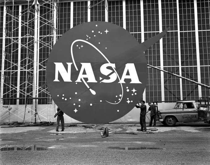 Workers install the NASA “meatball” logo on the front of the Flight Research Building, or hangar, at Lewis Research Center (now NASA Glenn) in 1962.
