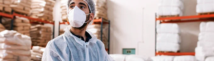 image of a man wearing a face covering and protective clothing inside a food warehouse