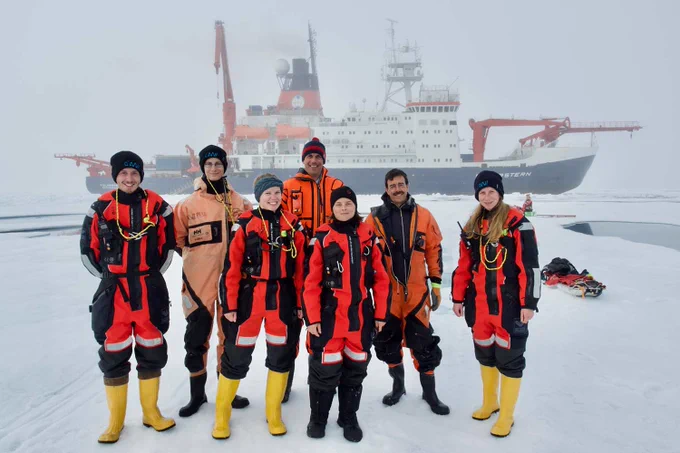 The photo shows seven researchers in the ice of the Arctis. The research vessel Polarstern can be seen in the background. Photo: Gunnar Spreen