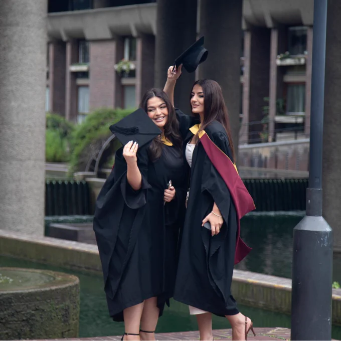 Two people posing with their graduation caps in the Barbican