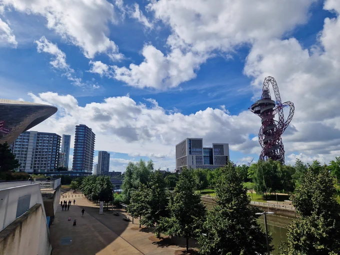 Sunny image of Queen Elizabeth Olympic Park, with blue sky's, whispey white clouds and the iconic aquatics center framing UCL East New campus.