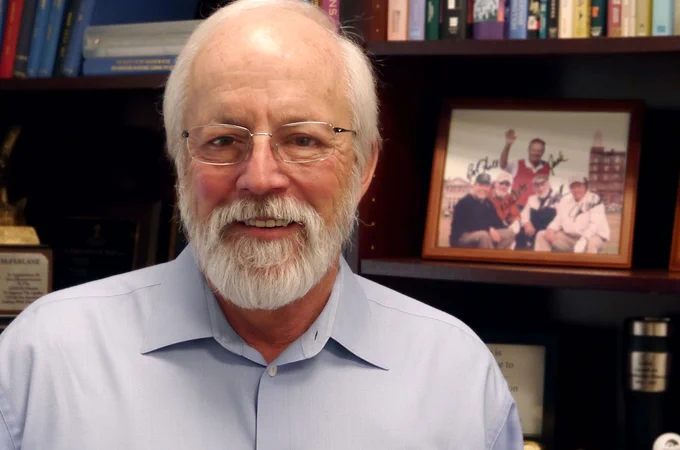 A smiling Fred McFarlane in front of a bookshelf.