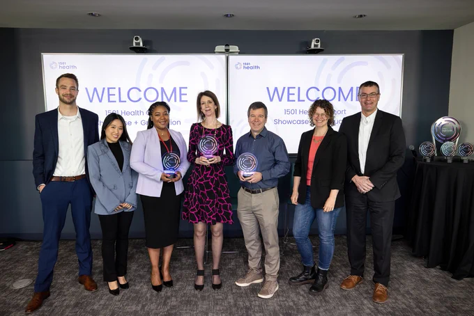 Several people stand in a line to pose for a picture, some of the hold awards.