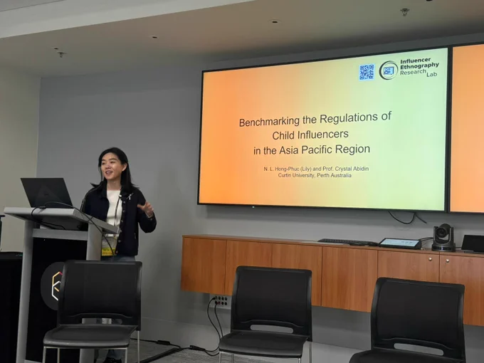 A photo of N.L. Hong-Phuc presenting at ICA2024. The paper she is presenting is "Benchmarking the Regulations of Child Influencers in the Asia Pacific Region", N. L. Hong-Phuc & Prof Crystal Abidin, Curtin University, Perth Australia. Influencer Ethnography Research Lab.
