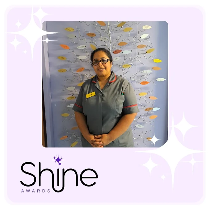 Suja, member of staff standing in corridor smiling 