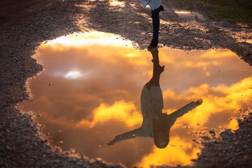 A women reflected in a puddle.
