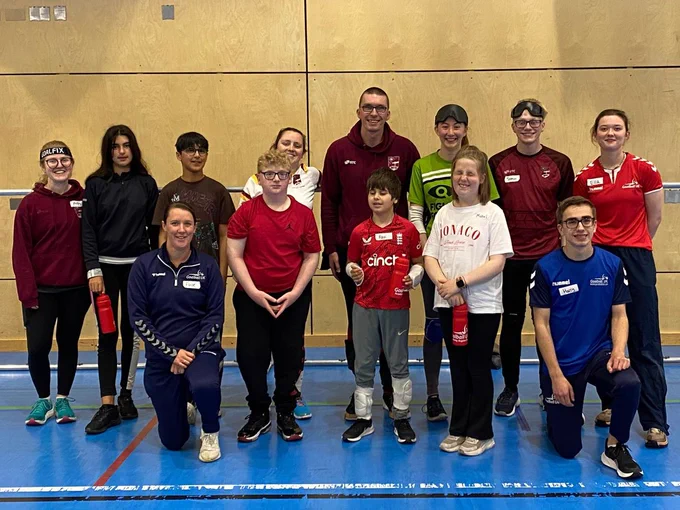 Attendees of the Northern Allstars Aspire Day where players, coaches, and Allstars volunteers are together in one photo across two rows. They are standing in front of a goalball goal after the session has finished, lots of smiley faces on show after a good session!