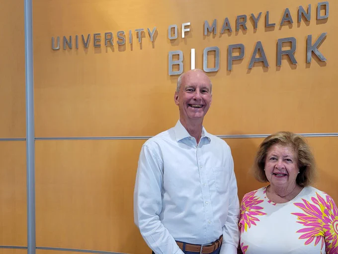 Two people standing in front of the "University of Maryland BioPark" sign on a wooden wall.