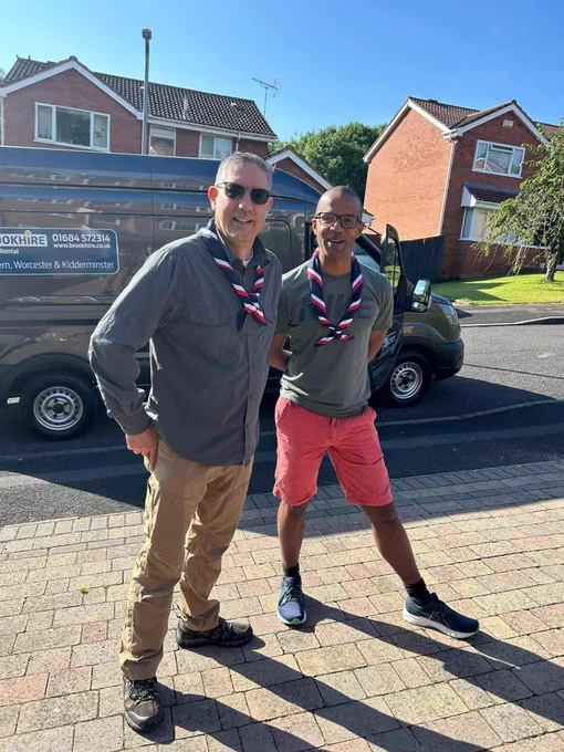 Two Scout Volunteers wearing neckerchiefs in front of a van