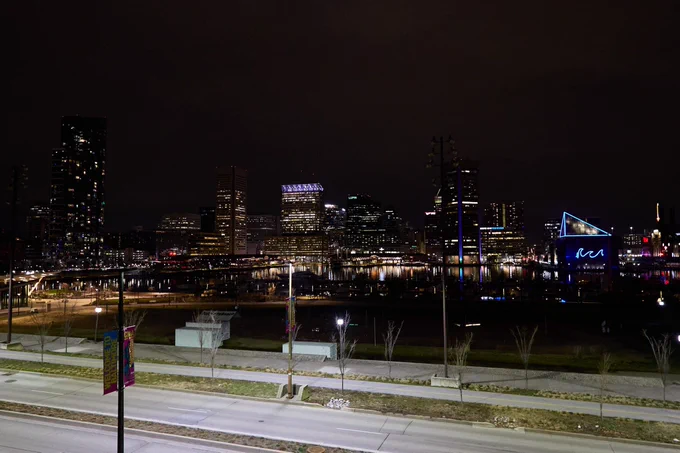 Baltimore skyline at night behind grey road.