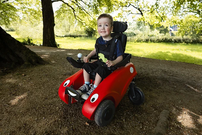 Frankie smiling at the camera while enjoying outside in his Wizzybug