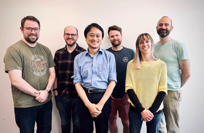 Six people standing in a room with Professor Sekimoto at the front. 