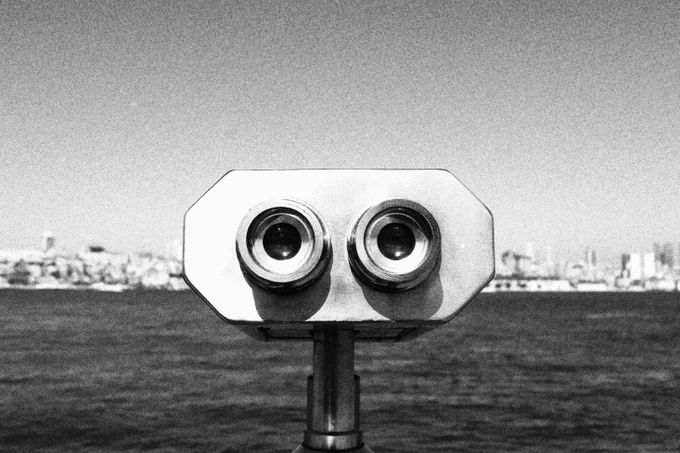 Black and white photo of a metal viewer in front of water.