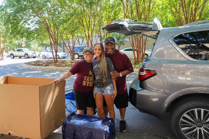 TXST student with family members at vehicle during move-in