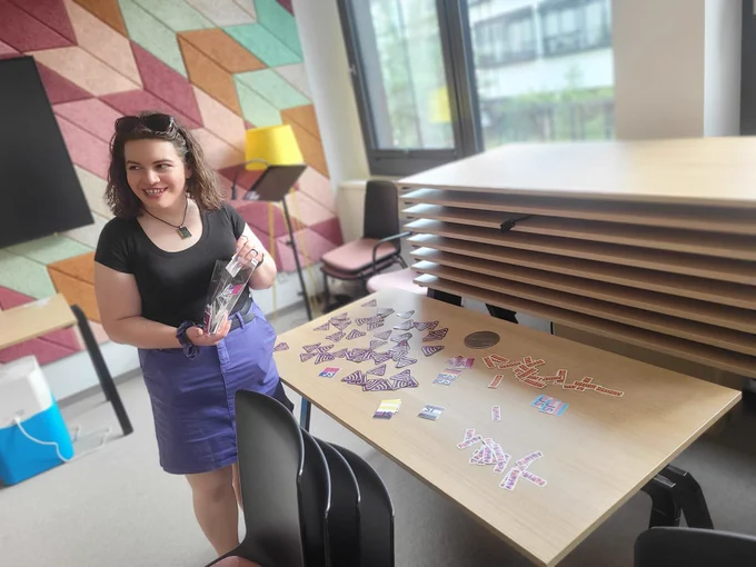 Carmen putting QueerJS stickers on a table also with sentry stickers
