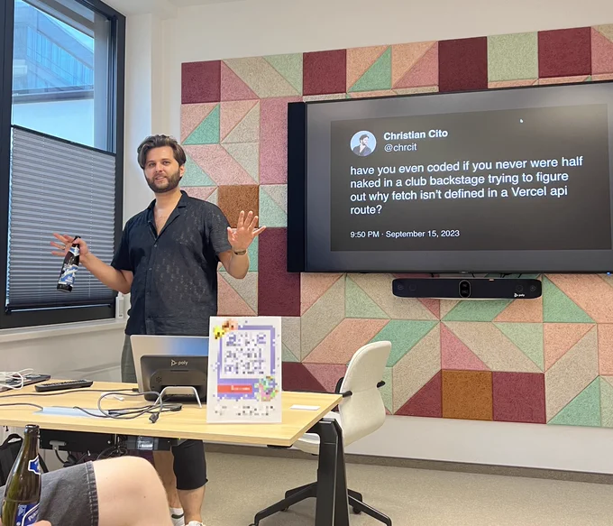 Me standing in front of a big screen which shows a tweet of mine from September 15, 2023 which says: 

"have you even coded if you never were half naked in a club backstage trying to figure out why fetch isn't defined in a Vercel api route? 