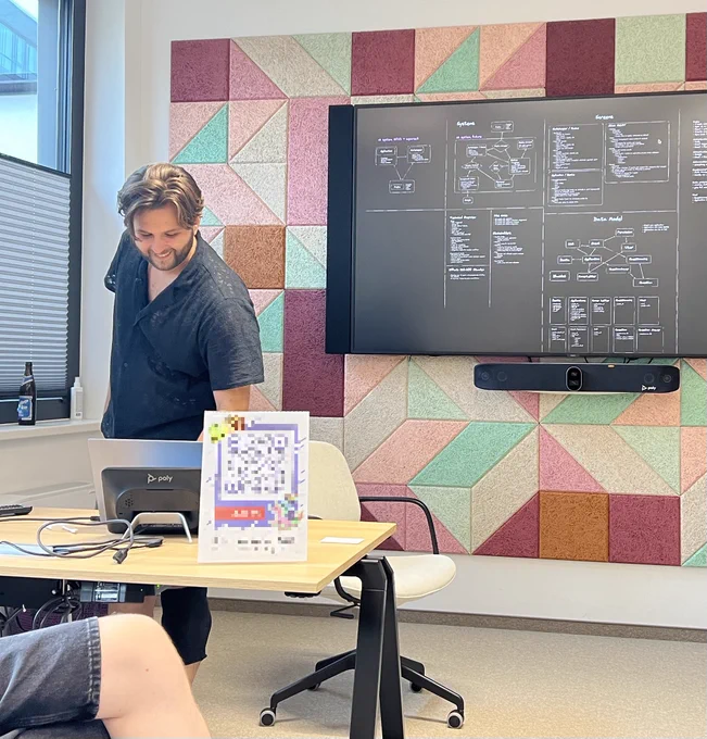 Me standing in front of a big screen which shows a barely readable highlevel architecture diagram of the application.