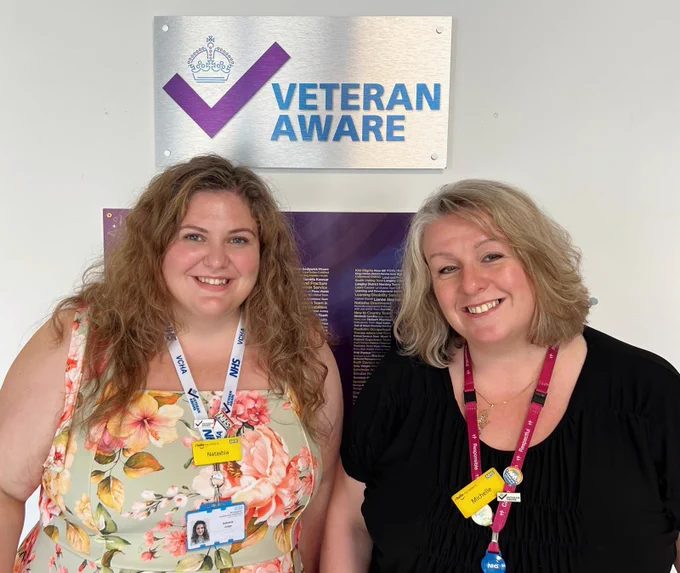 Natashia Judge, Veteran Aware Programme Lead and Chief Governance Officer and Veteran Aware Executive Lead, Michelle Alli pictured in front of BCHC's veteran aware accreditation plaque.