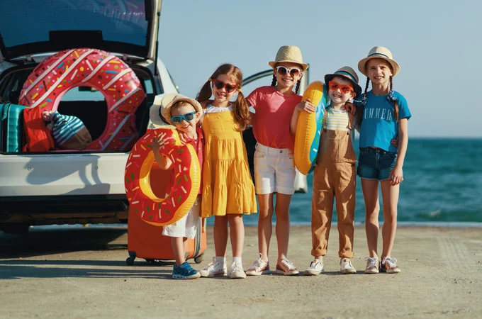 Group of kids carrying beach gear for a day on the beach