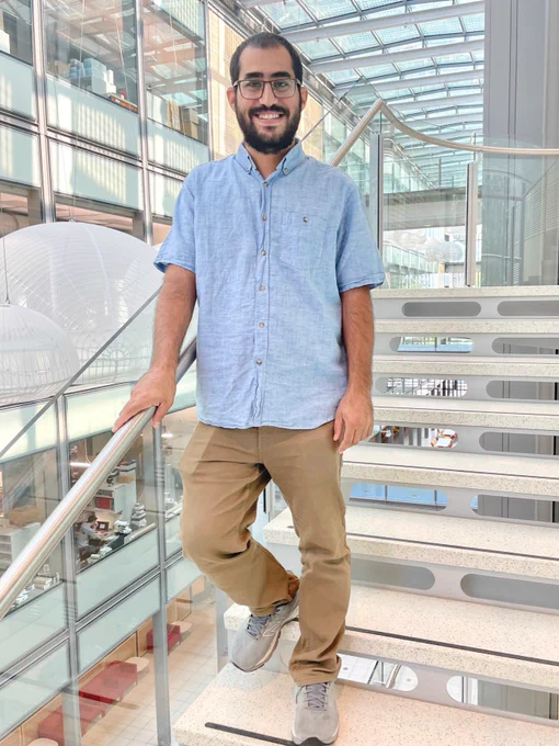 Full-color photo of Qais standing on the staircase in Princeton Chemistry's Frick Lab.