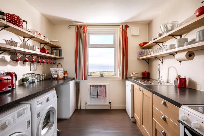 The kitchen with white goods under the counter tops and open shelves above