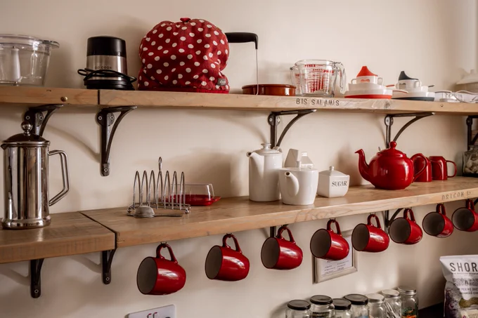 Kitchen shelves with mugs, teapots and coffee pots and a toast rack