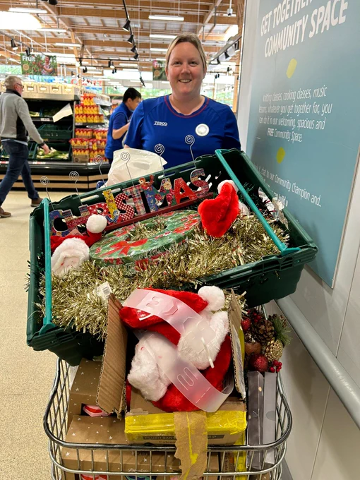 A Tesco colleague with a shopping trolley overflowing with Christmas decorations. 