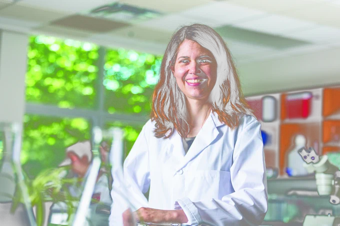 Dr. Erin Cameron poses in a lab wearing a white lab coat. 