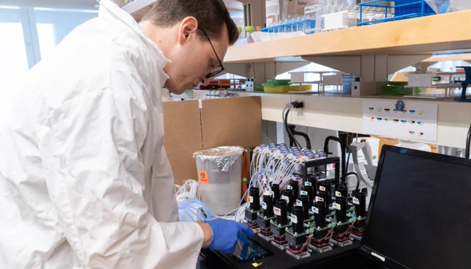 PhD candidate Karol Buda leans over equipment in the Tokuriki lab to analyze a sample.