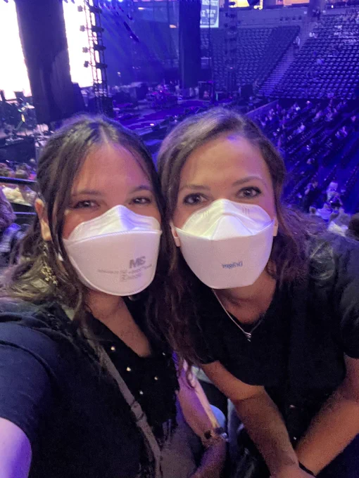 Two brunette white females wearing white respirators at an arena.