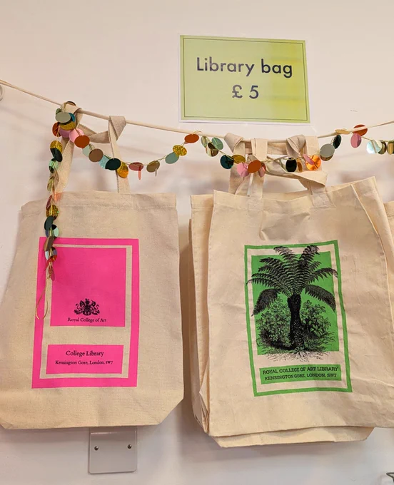 A photo of two RCA Library tote bags, one with a hot pink RCA logo, and one with a picture of a fern tree in green.