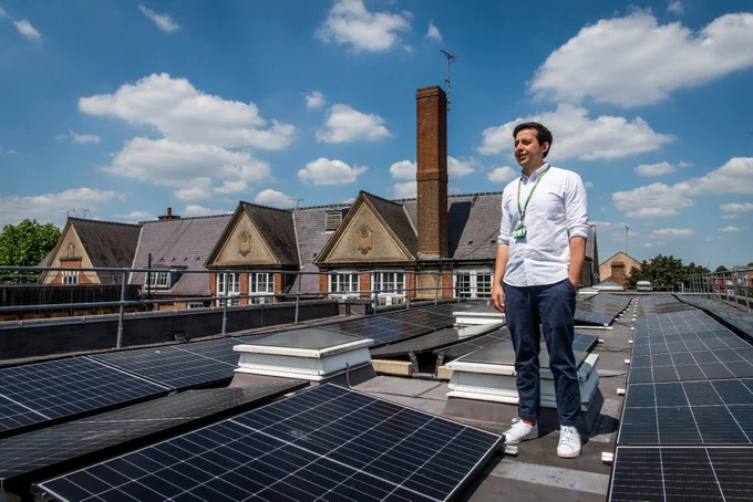 Alex De Lange, assistant head at Springfield Community Primary School, standing by the school's solar panels with the school building in the background. 