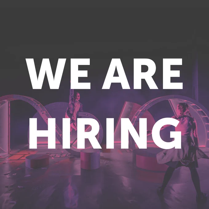 The text 'WE ARE HIRING' is atop an image of a stage with dramatic lighting, a jungle gym like set, and two actors running around it