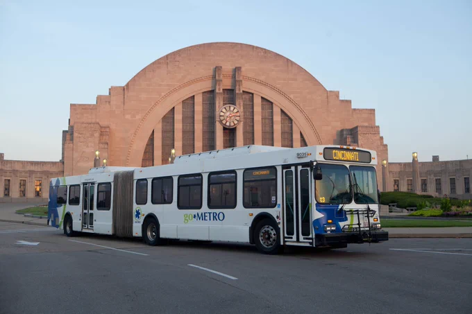 Photo from 2015 featuring one of Metro's articulated buses in front of the Cincinnati Museum Center at sunset. 