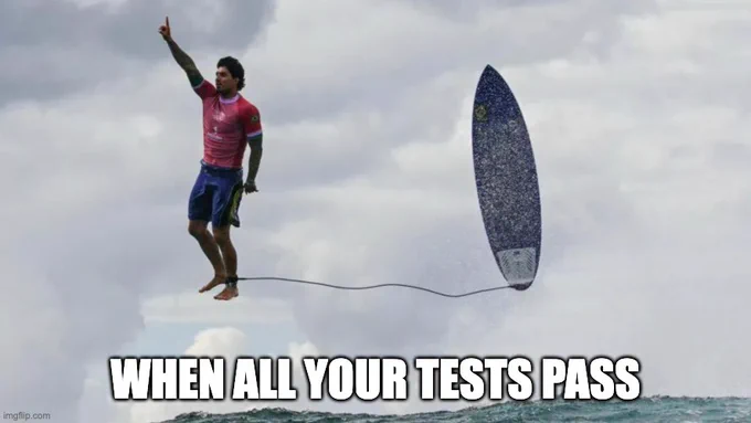 A surfer looking chuffed and cool standing above a big wave with his arm up in the air, looking like he's standing on a cloud in the background. Text: when all your tests pass.