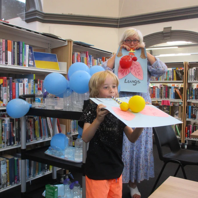 boy and member of staff inflating balloons