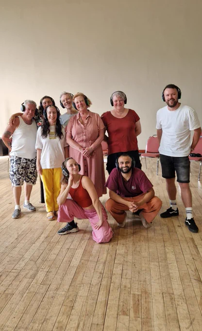 A group of people standing and smiling in colourful clothing in a dance studio