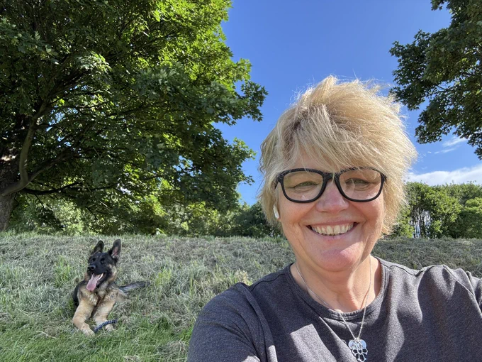 Smiling woman selfie with German Shepherd dog  sitting in the background
