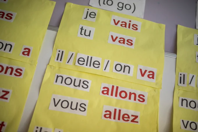 A poster in a school - on a yellow background text says: Je vais. Tu vas. Il / elle / on va. Nous allons. Vous allez.