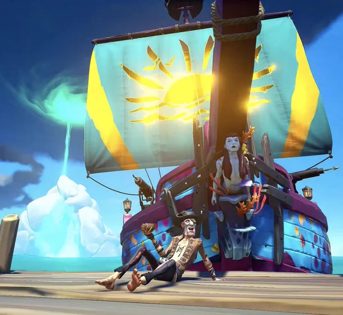 A pirate relaxes on a dock in front of their ship, which proudly flies a set of sails that are blue with a golden emblem of a sun in the centre.